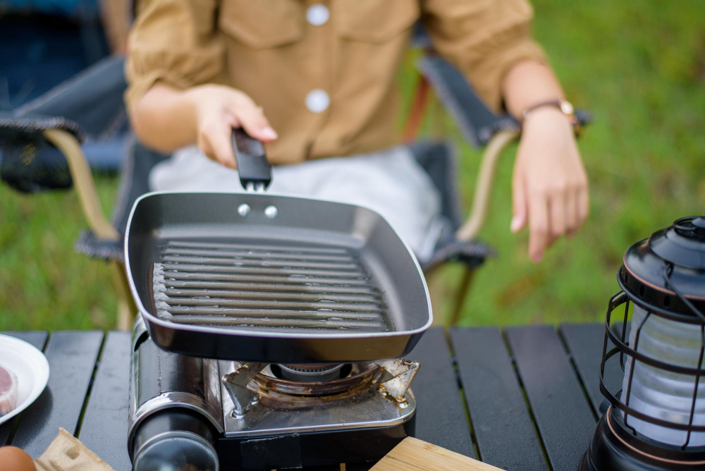 closeup happy young asian woman preparing oil hot pan while sitting chair camping site